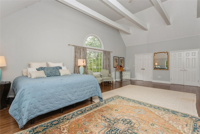 bedroom featuring wood finished floors, beam ceiling, high vaulted ceiling, baseboards, and multiple closets