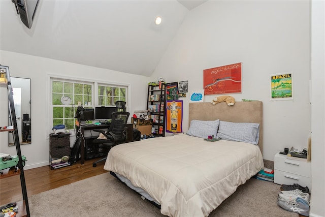 bedroom with wood finished floors, high vaulted ceiling, and baseboards