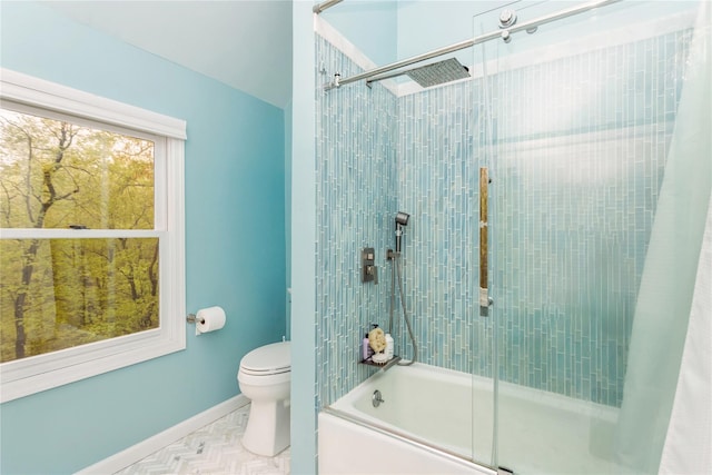 bathroom with toilet, combined bath / shower with glass door, and baseboards