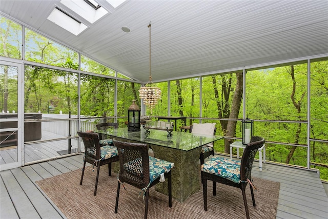 sunroom featuring lofted ceiling, a skylight, and a chandelier