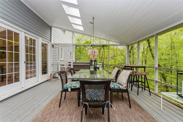 sunroom with lofted ceiling, a skylight, outdoor dining area, and healthy amount of natural light