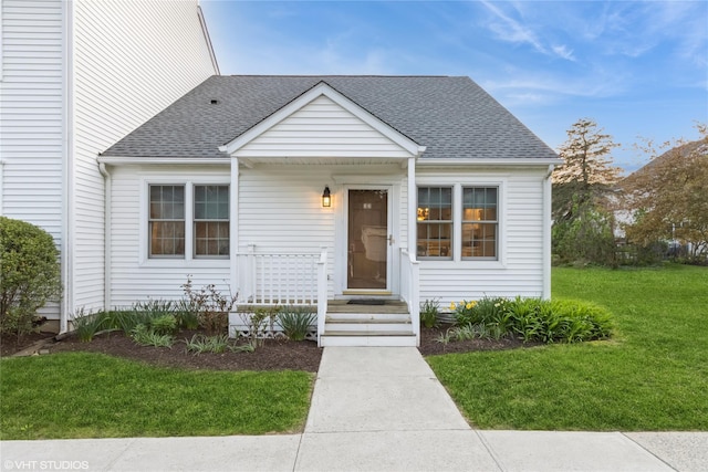 view of front of home with roof with shingles and a front yard