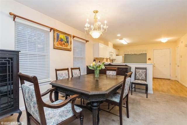 dining area with baseboards, a notable chandelier, and light carpet