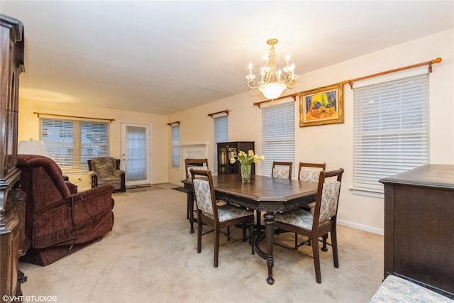dining area featuring light colored carpet, baseboards, a fireplace, and an inviting chandelier