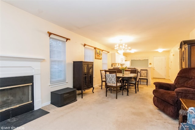 dining space with baseboards, carpet flooring, a fireplace with flush hearth, and a chandelier