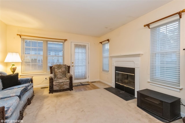 carpeted living room featuring baseboards and a fireplace with flush hearth