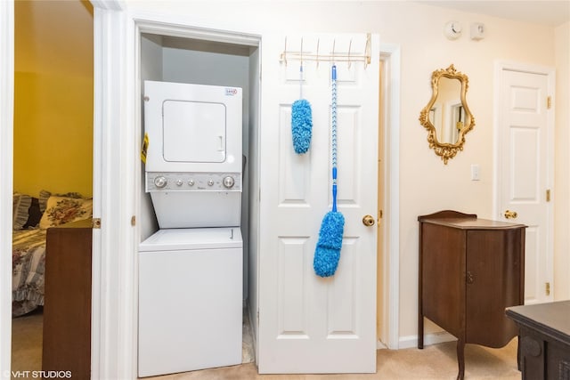laundry area featuring laundry area, baseboards, and stacked washer / dryer