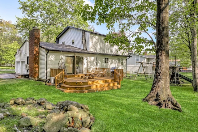 back of property with a chimney, a wooden deck, and a yard