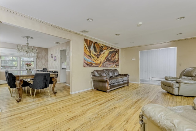living room with a chandelier, wood finished floors, baseboards, a baseboard heating unit, and crown molding