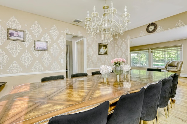 dining room featuring a chandelier, wallpapered walls, and wood finished floors