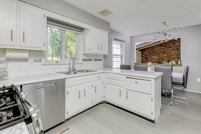 kitchen with a sink, stainless steel dishwasher, light countertops, white cabinets, and brick wall