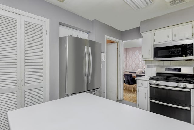 kitchen featuring appliances with stainless steel finishes, light countertops, white cabinetry, and backsplash
