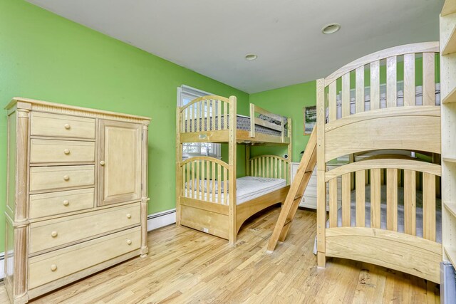 bedroom with light wood-style floors, a baseboard heating unit, and baseboards