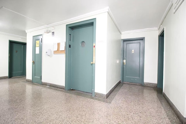 interior space with crown molding, baseboards, and speckled floor