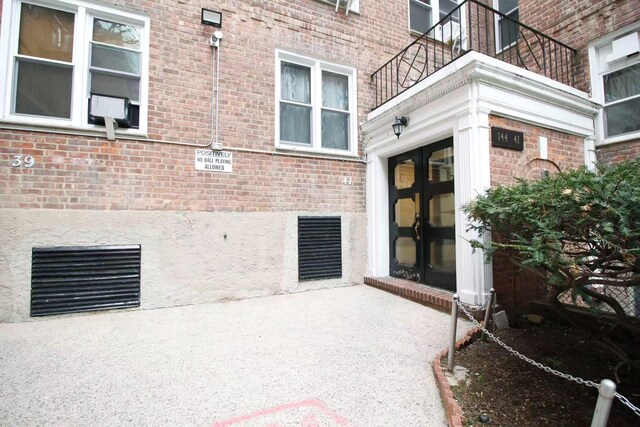 property entrance featuring brick siding, french doors, and a balcony