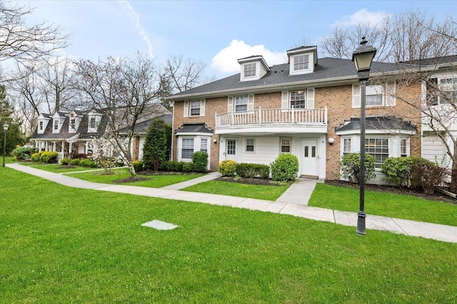 multi unit property with a balcony, brick siding, and a front yard