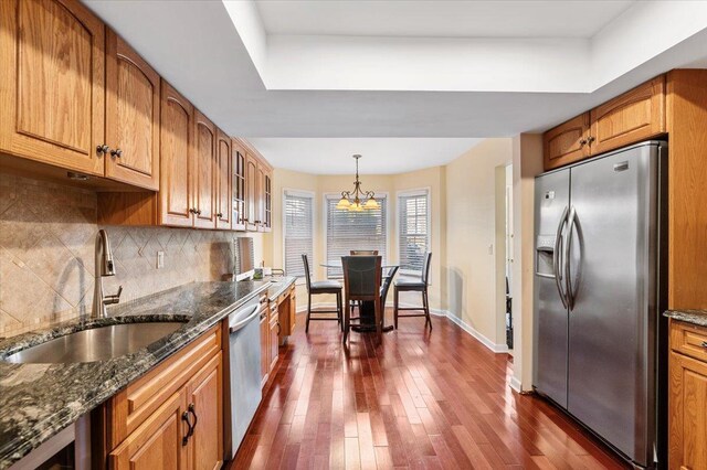 kitchen featuring a sink, appliances with stainless steel finishes, tasteful backsplash, and dark wood-style flooring