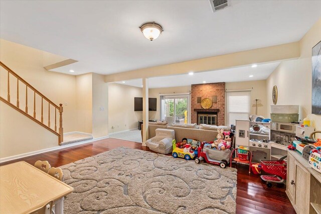 rec room with baseboards, a brick fireplace, hardwood / wood-style flooring, and visible vents