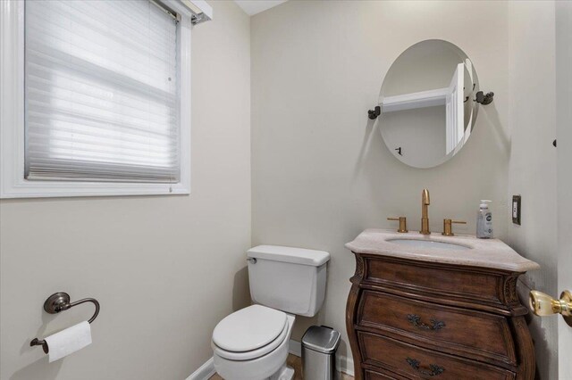 half bath featuring vanity, baseboards, and toilet