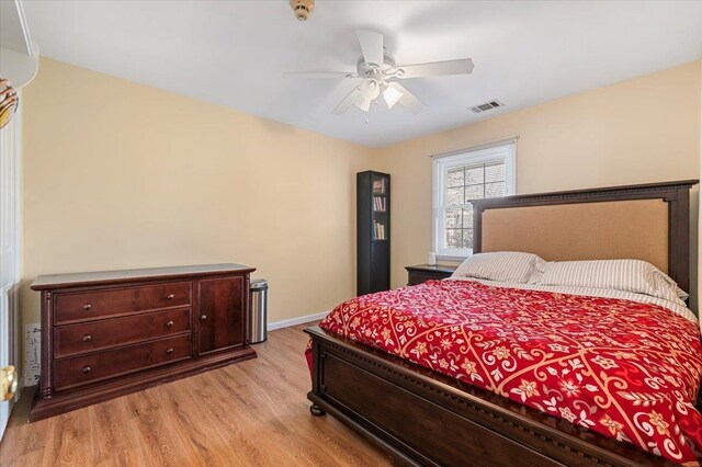 bedroom with ceiling fan, visible vents, baseboards, and light wood finished floors