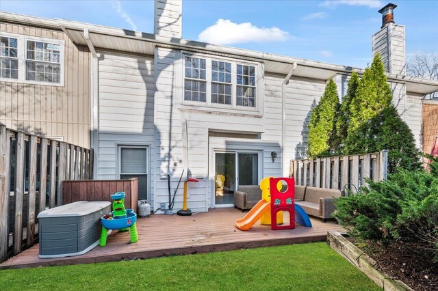 rear view of house with fence, a wooden deck, and a chimney
