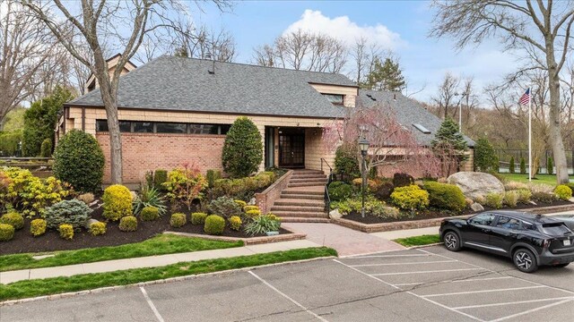 view of front of home featuring uncovered parking, roof with shingles, a chimney, and fence