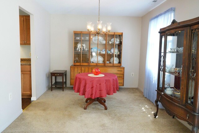 carpeted dining area with a chandelier