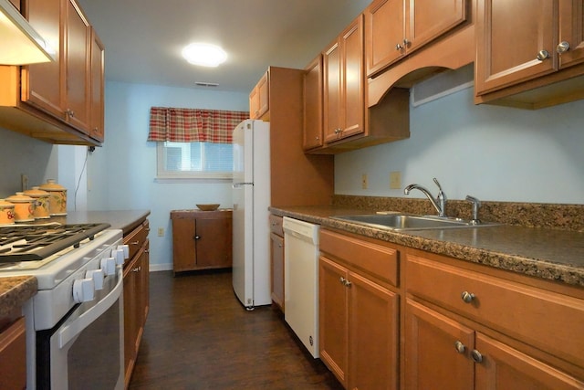 kitchen with dark countertops, a sink, white appliances, visible vents, and dark wood-style floors