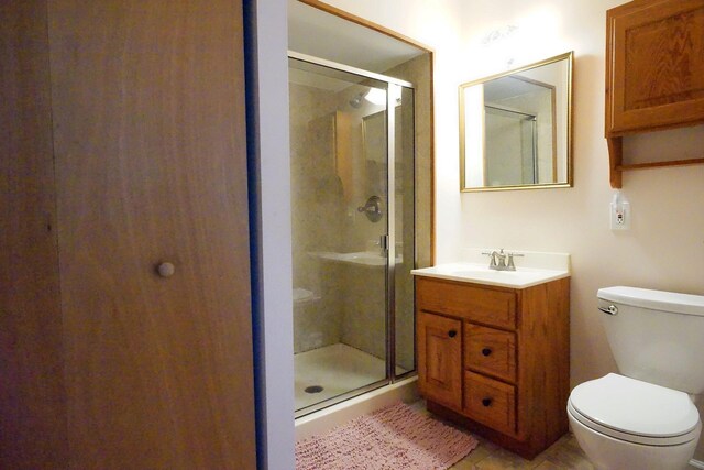 bathroom featuring vanity, tile patterned flooring, a stall shower, and toilet
