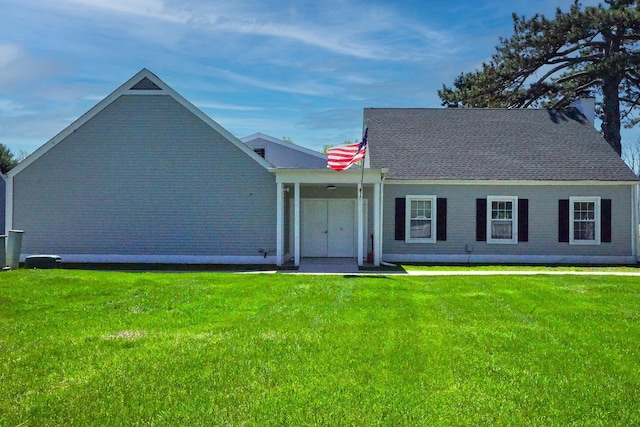 view of front facade featuring a shingled roof and a front yard