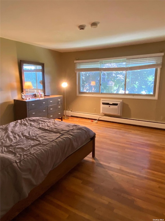 bedroom featuring multiple windows, a wall mounted air conditioner, and wood finished floors