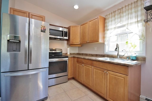 kitchen with baseboard heating, a sink, light tile patterned floors, vaulted ceiling, and stainless steel appliances