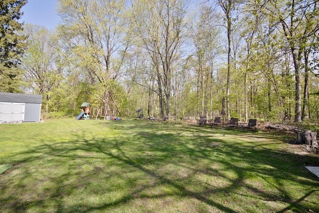view of yard featuring a playground, an outdoor structure, and a storage shed