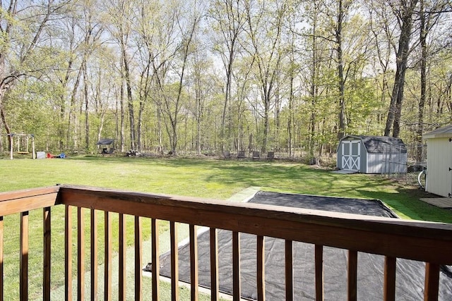 deck with a storage unit, a lawn, and an outbuilding