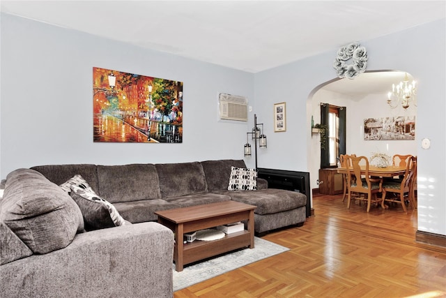 living area featuring arched walkways, an AC wall unit, and a chandelier