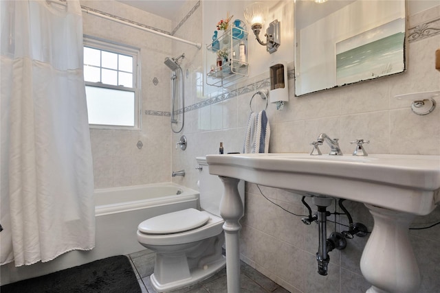 bathroom with shower / bath combo with shower curtain, toilet, and tile walls