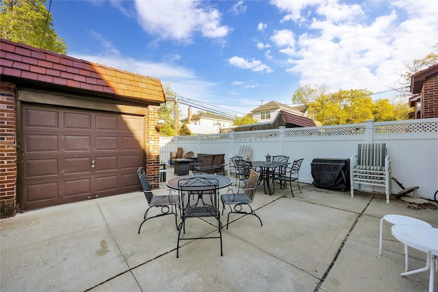 view of patio / terrace featuring outdoor dining area, a garage, and fence