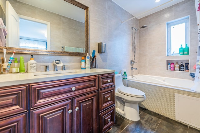 bathroom with tile patterned flooring, vanity, toilet, tile walls, and tiled shower / bath combo