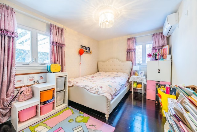 bedroom with a wall mounted air conditioner and wood finished floors
