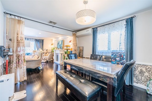dining area featuring visible vents, wood finished floors, and a wall mounted air conditioner