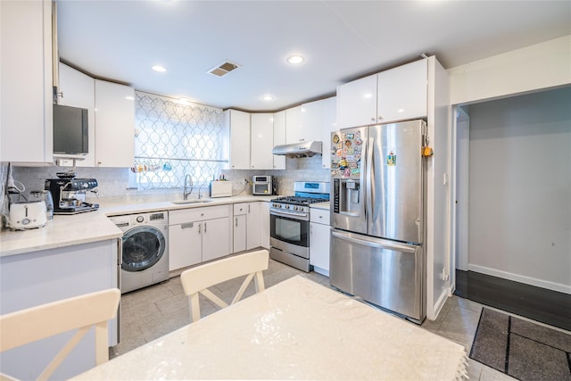 kitchen with appliances with stainless steel finishes, tasteful backsplash, a sink, washer / dryer, and under cabinet range hood