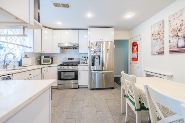 kitchen featuring backsplash, visible vents, appliances with stainless steel finishes, a sink, and under cabinet range hood