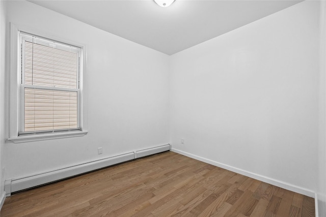 spare room with baseboards, baseboard heating, and wood finished floors