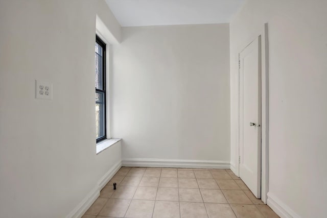 spare room featuring light tile patterned floors and baseboards