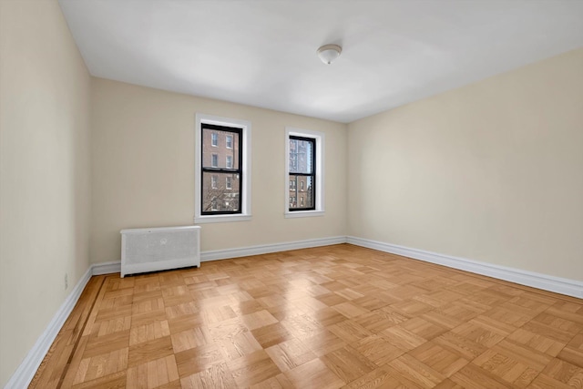 unfurnished room featuring baseboards and radiator