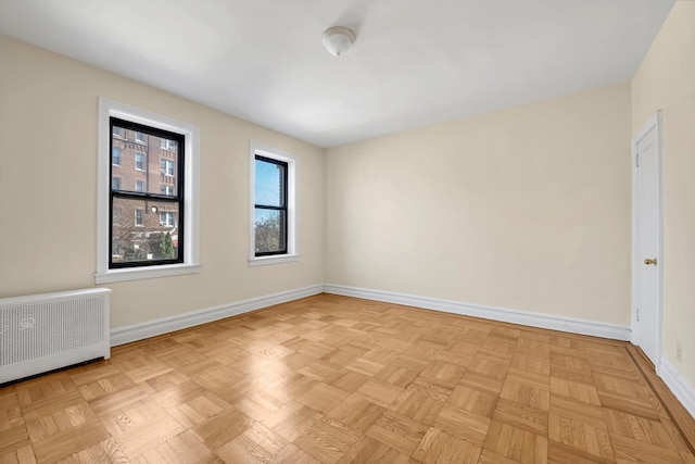 unfurnished room with baseboards and radiator