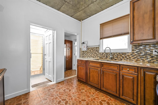 87-71 111th St, Richmond Hill, NY 11418 - kitchen with decorative backsplash, light stone countertops, baseboards, brown cabinets, and a sink