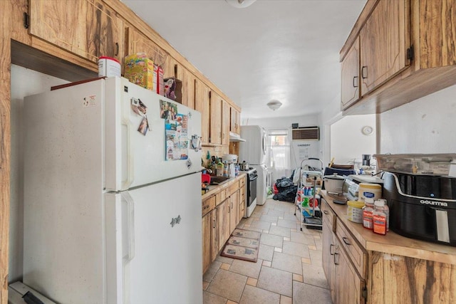 kitchen featuring range, freestanding refrigerator, stone tile floors, light countertops, and an AC wall unit