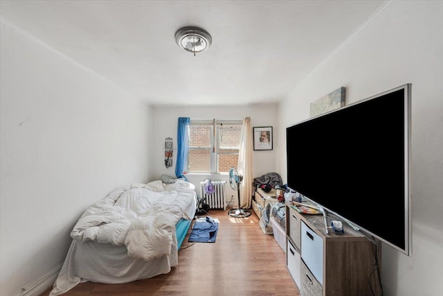 bedroom featuring radiator heating unit and wood finished floors