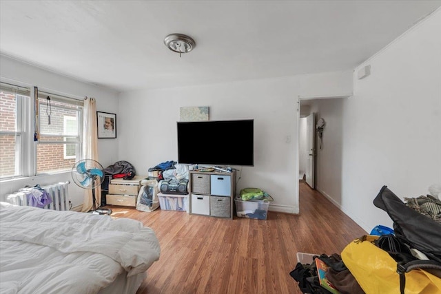 bedroom with baseboards, radiator, and wood finished floors